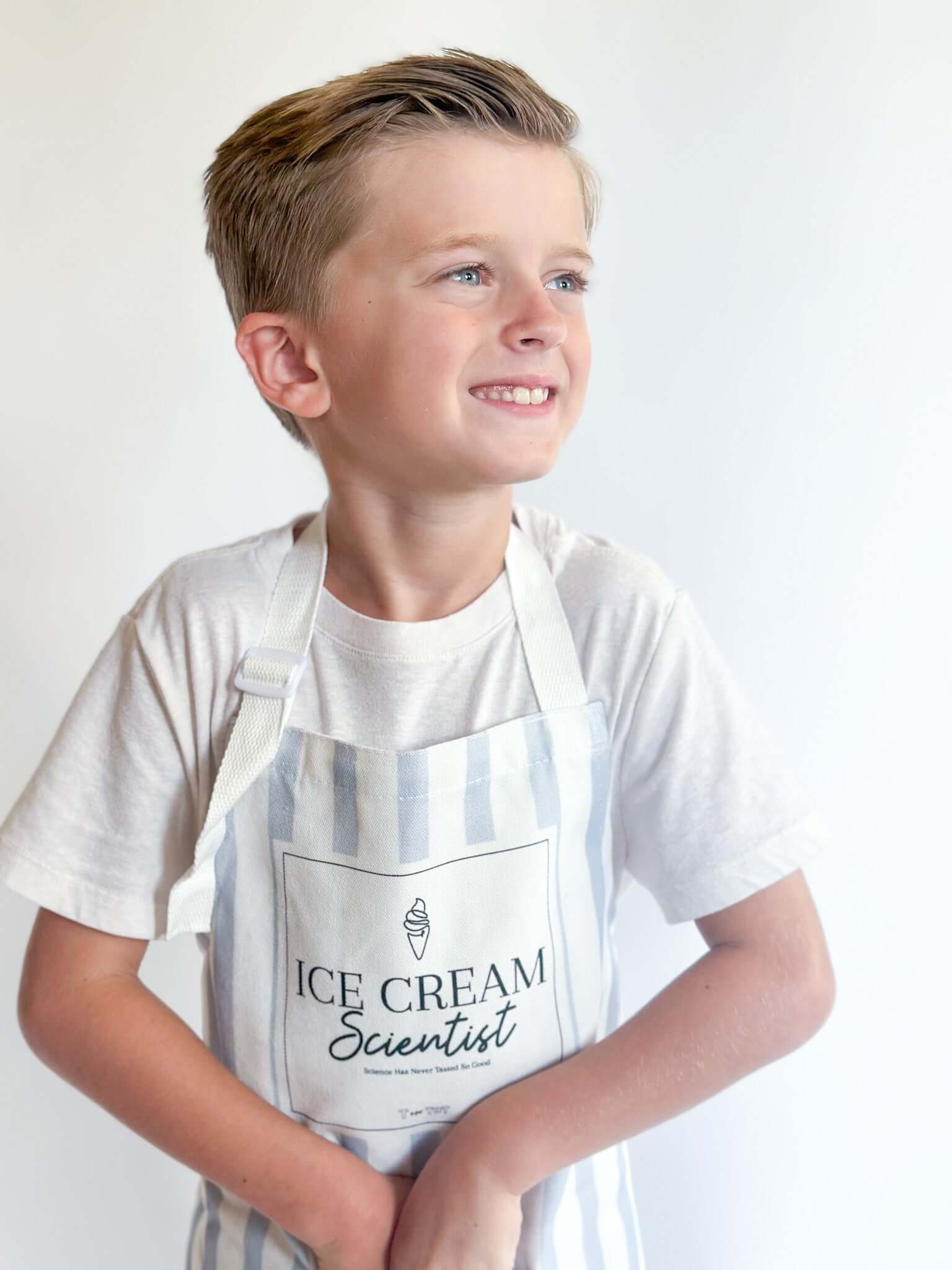Smiling child wearing an ice cream scientist apron, ready for fun and creative science play.